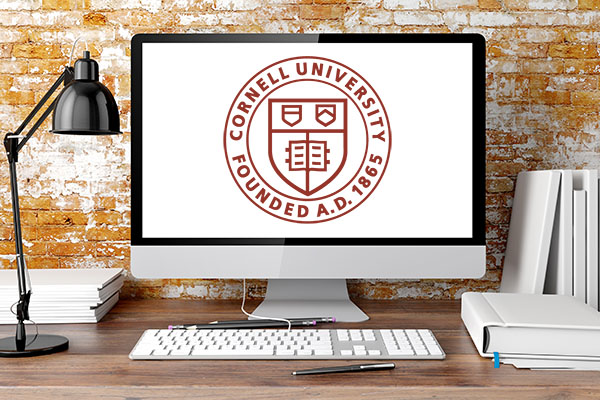 Computer screen on a desk, displaying the Cornell University seal on a white screen