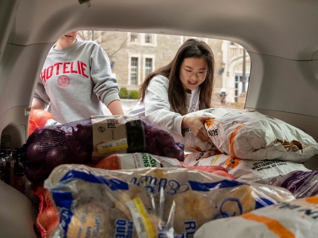 Two SHA students unloading produce from a car trunk